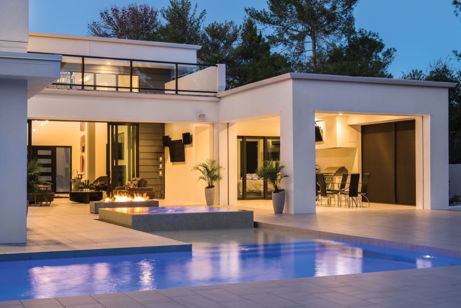 Backyard with a pool and lit fire pit at dusk. An open floor plan shows the home’s lighting and design. 