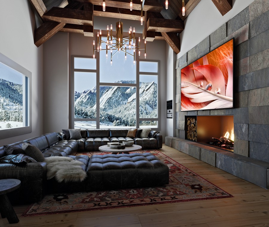 A living area with a large flat-screen TV above a fireplace and views of the mountains.